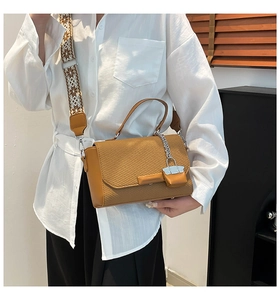 Detailed view of camel woven shoulder bag with wide geometric strap and metallic chain