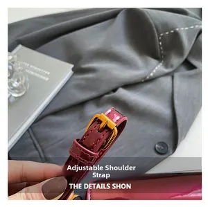 Détail de la bandoulière réglable avec boucle dorée sur un sac en cuir verni bordeaux