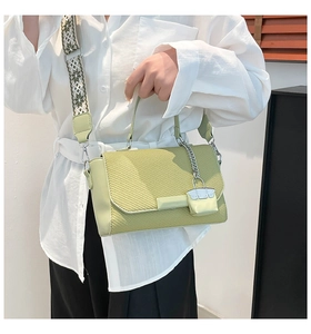 Detailed view of light green crossbody bag with woven texture and floral strap on model