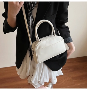Detail of white mini Boston bag with silver hardware on a model in a black blazer