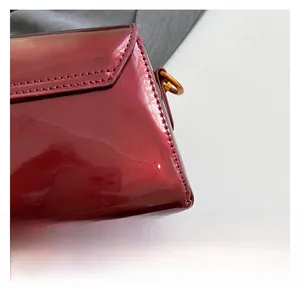 Gros plan sur le cuir verni bordeaux brillant avec paillettes et détails dorés en métal