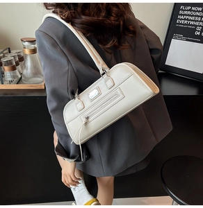 Gros plan d'un sac sous le bras blanc avec logo argenté et texture cuir élégante