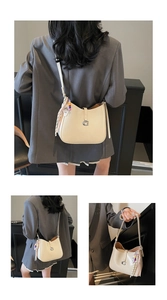 Detail of cream patent leather handbag featuring silver G-buckle and colorful beaded charm