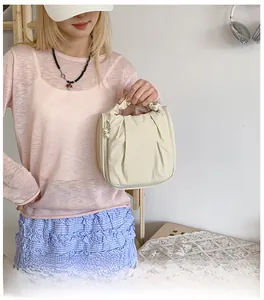 Detail of cream pleated makeup bag with elastic handle and pearl zipper charm