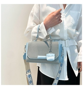 Detail of sky blue and off-white crossbody bag with wide patterned strap and silver hardware