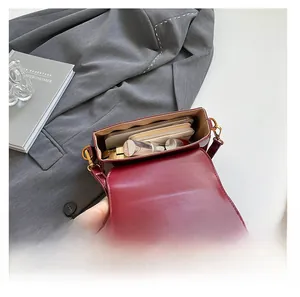 Détail de l'intérieur du sac à rabat en cuir bordeaux montrant sa grande capacité de rangement