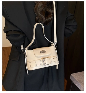 Détail d'un sac seau en cuir crème avec sangle à œillets et fermoir rotatif métallique