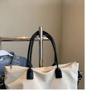 Détail du grand sac cabas en toile beige avec des poignées en cuir noir renforcé