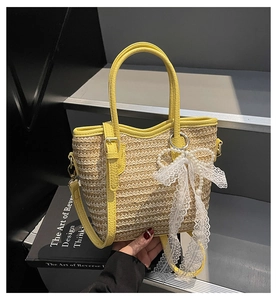 Detail of yellow woven straw bucket bag with white pearl charm and lace bow decor