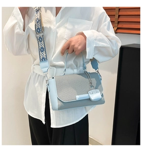Detail of light blue crossbody bag with woven texture flap and wide printed shoulder strap