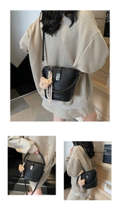 Detail of black leather bucket bag with silver twist lock and plush bear charm