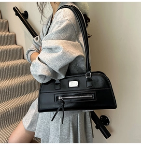 Vue détaillée d'un sac sous le bras noir brillant avec plaque en métal dans l'escalier