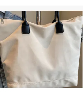 Gros plan du sac fourre-tout crème avec poignées noires et tissu à texture douce