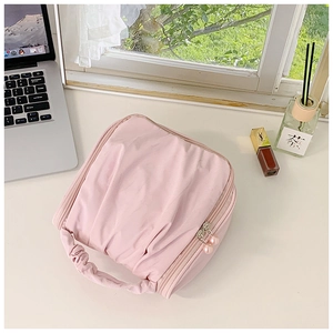 Pink pleated handbag with pearl zipper detail on a minimalist vanity desk setup