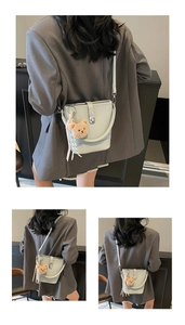 Detail view of mint green bucket bag featuring litchi texture and a brown bear charm