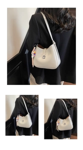 Detail of white patent leather shoulder bag with silver G-buckle and colorful tassel charm