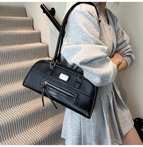 Détail d'un sac sous les bras noir avec boucles argentées et style motard rétro tendance