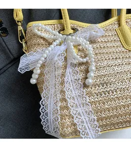 Detail of hand-woven straw bucket bag featuring yellow leather trim and pearl lace charm