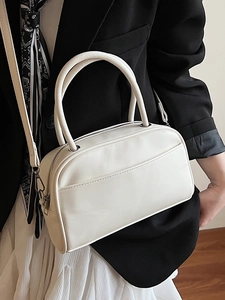 Minimalist beige crossbody pillow bag with top handles and front pocket shown on model