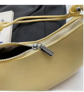 Detail of smooth metal zipper and premium light yellow faux leather on a hobo bag