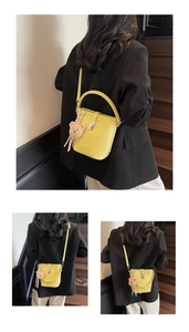 Detail of yellow leather bucket bag with brown teddy bear charm and silver metal hardware