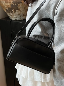 Minimalist black leather Boston pillow bag with top handles and adjustable shoulder strap