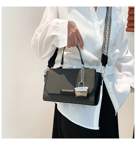 Close-up of black woven square handbag with jacquard wide strap and silver chain detail