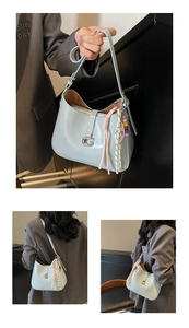 Close-up of light blue patent leather underarm bag with G-shaped logo and beaded charm