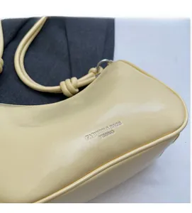 Detailed close-up of light yellow glossy PU leather bag with side logo embossing