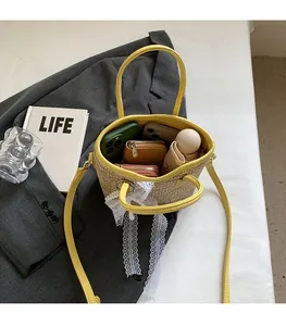 Straw bucket bag detail showing yellow leather trim and spacious interior storage