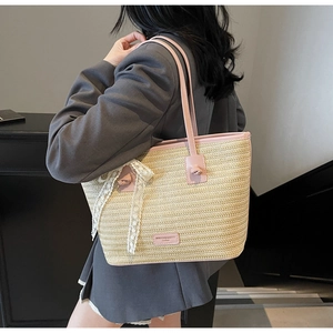 Vue détaillée du sac cabas en paille avec bordure en cuir rose et nœud en dentelle blanche