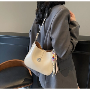 Detail of off-white faux leather hobo bag with silver G-buckle and colorful beaded tassel