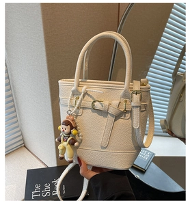 Detailed macro view of cream lychee texture leather with a cute doll pendant charm