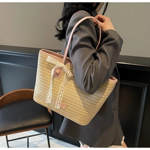 Détail du sac cabas en paille tissée avec anses en cuir rose et nœud en dentelle blanche