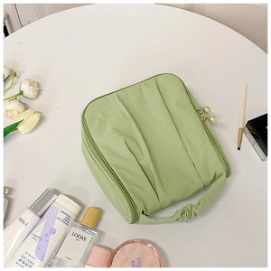 Detail of light green ruched cosmetic bag with pearl zippers and makeup accessories