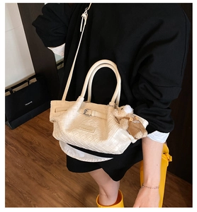 Detail of cream woven bucket bag with leather texture and cute plush bear charm accessory