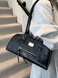 Sac sous le bras minimaliste en cuir noir avec plaque argentée porté par un mannequin