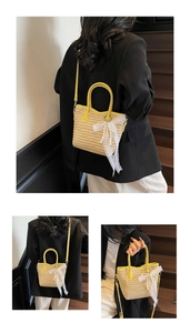 Detail of straw bucket bag featuring yellow leather trim and white lace bow with pearls