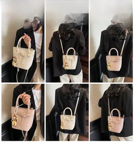 Detail view of stylish bucket bag with leather strap buckle and pearl chain decoration