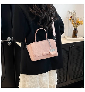 Pink crossbody bag detail featuring woven texture and jacquard strap on a black blazer