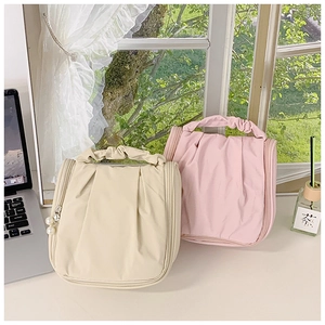 Detail of pleated makeup bag showing pearl zipper and stylish ruched handle texture