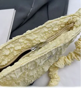 Close-up of a pale yellow textured cloud bag showing smooth silver metal zipper detail