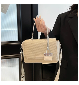Detail view of beige woven texture handbag featuring decorative silver lock and wide strap