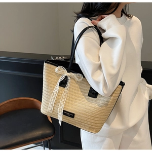 Détail du sac cabas en paille beige avec nœud en dentelle blanche et anses en cuir