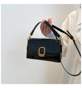 Gros plan du sac bandoulière en cuir verni noir avec boucle rectangulaire dorée chic