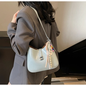 Close-up of light blue patent leather underarm bag with silver G buckle and charms
