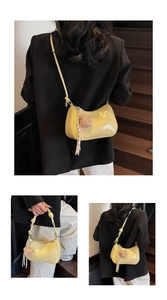Detail view of yellow crescent shoulder bag with bear pendant and silk ribbon decoration