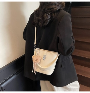 Detail view of cream white bucket bag with silver twist lock and plush bear pendant