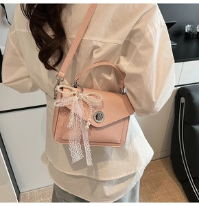 Détail du sac à main en cuir rose avec nœud en dentelle perlée et fermoir rotatif argenté