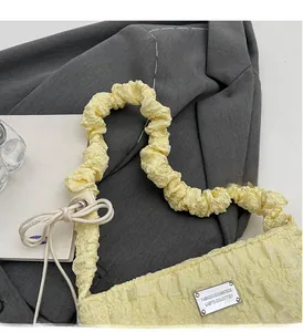Detail of light yellow ruched cloud bag featuring bubble texture and wavy handle design